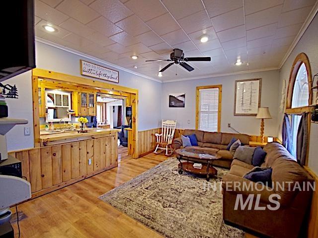 628 3rd Avenue South Payette, ID 83661 - Photo 5 of 19 Living room featuring wainscoting, wooden walls, light wood-type flooring, ornamental molding, and a ceiling fan
