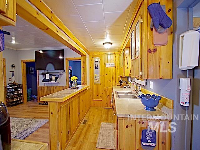 628 3rd Avenue South Payette, ID 83661 - Photo 7 of 19 Kitchen with wood walls, light wood-style floors, light countertops, a peninsula, and a wainscoted wall