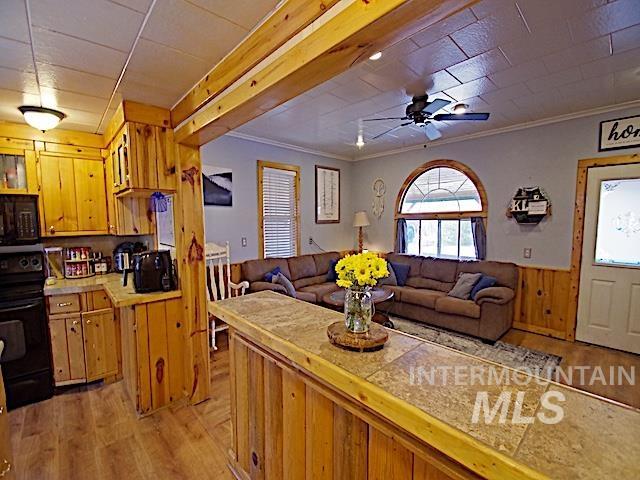 628 3rd Avenue South Payette, ID 83661 - Photo 19 of 19 Kitchen featuring light wood finished floors, black appliances, open floor plan, a wainscoted wall, and wood walls