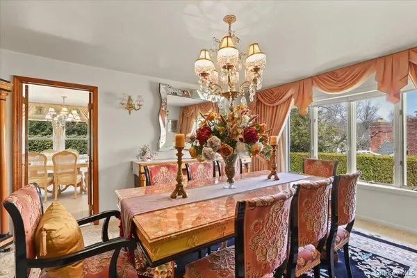 a view of a dining room with furniture a chandelier and large windows