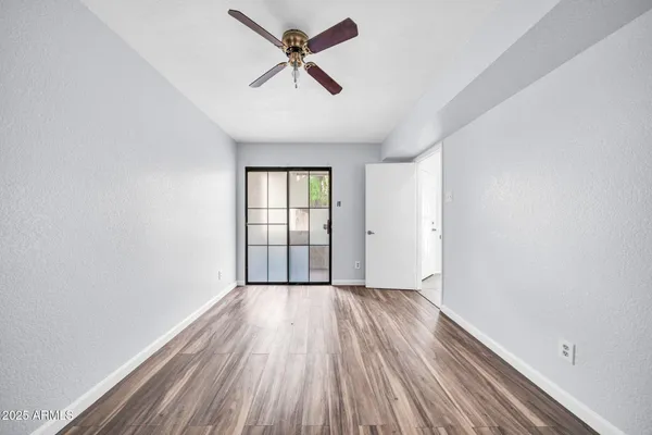 an empty room with wooden floor fan and windows