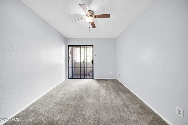 an empty room with chandelier fan and windows