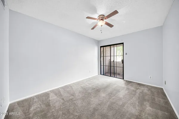 an empty room with windows and fan