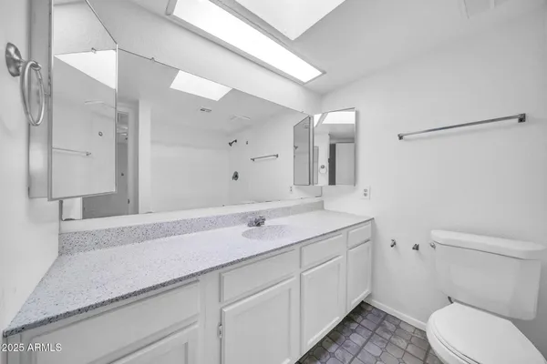 a bathroom with a granite countertop sink a toilet and a mirror