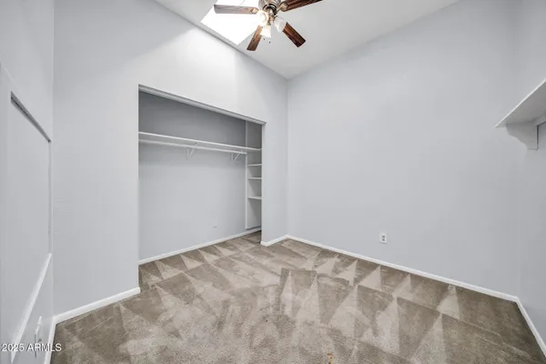 an empty room with a ceiling fan and carpet