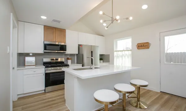 a kitchen with stainless steel appliances a sink a stove a refrigerator dining table and chairs