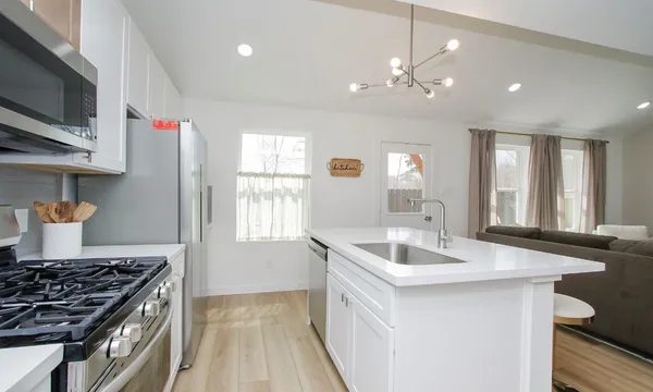 a kitchen with a sink and a stove top oven with wooden floor