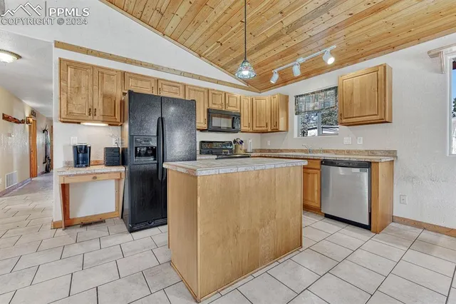a kitchen with stainless steel appliances granite countertop a refrigerator a sink a stove top oven and cabinets