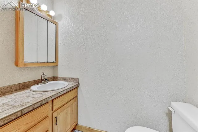 a bathroom with a granite countertop sink and a mirror with toilet