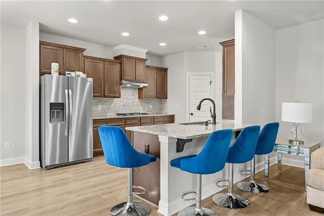 a kitchen with stainless steel appliances granite countertop a sink a stove a refrigerator and island with wooden floor