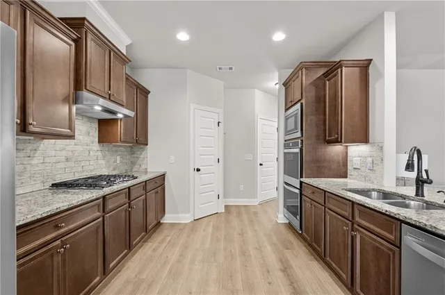a kitchen with stainless steel appliances granite countertop a refrigerator a stove and a sink