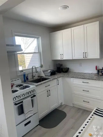 a kitchen with granite countertop white cabinets and white appliances