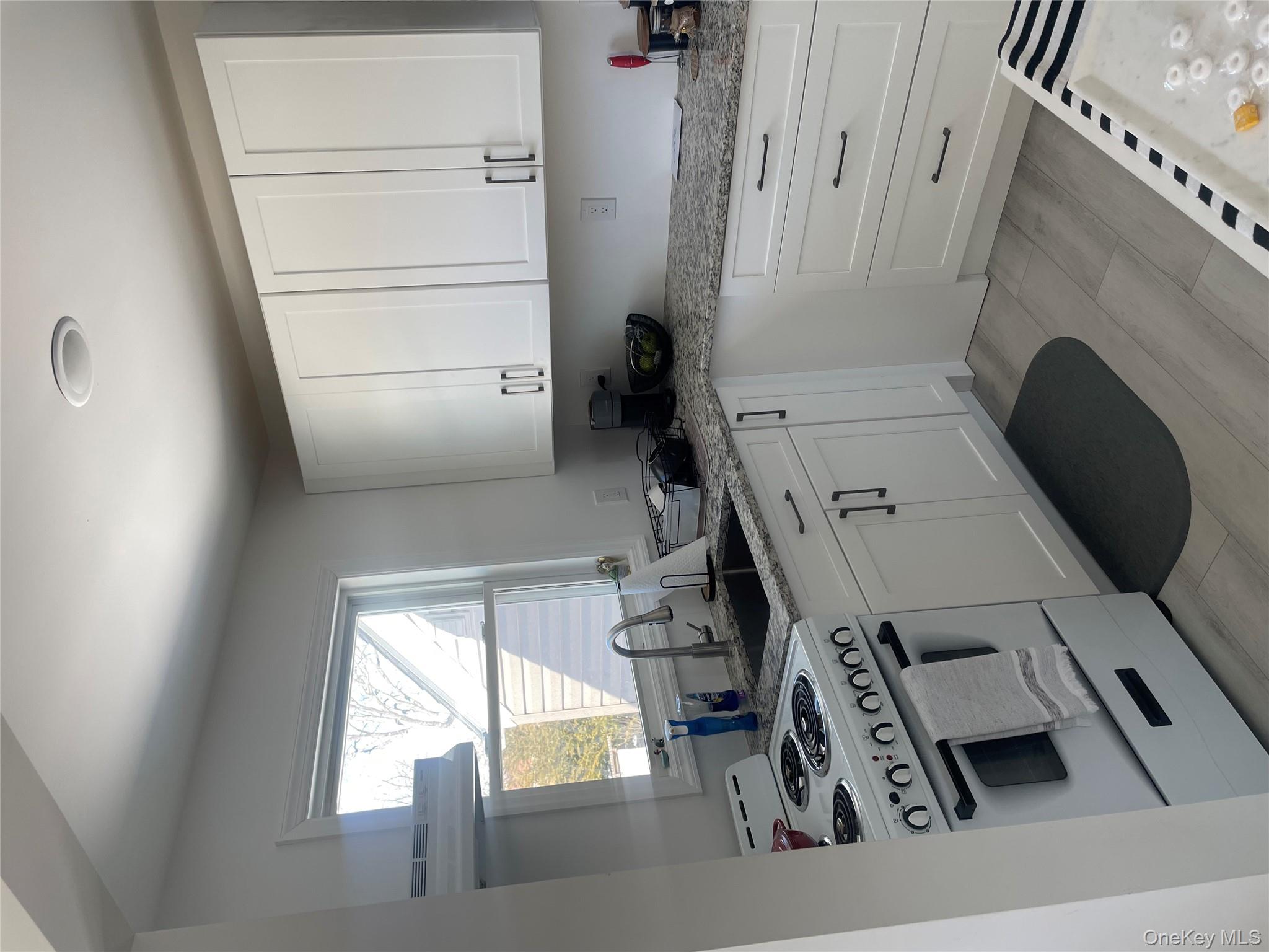 a kitchen with granite countertop white cabinets and white appliances
