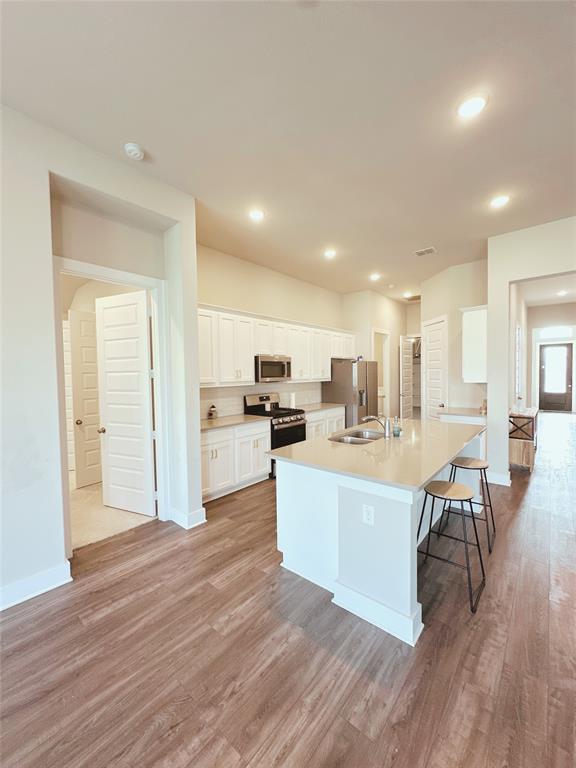 1304 Caprock Drive Forney, TX 75126 - Photo 11 of 15 Kitchen featuring white cabinets, a kitchen breakfast bar, light wood-style floors, a center island with sink, and recessed lighting
