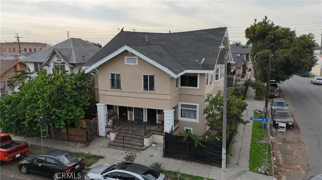 a view of a house with a cars park side of a road