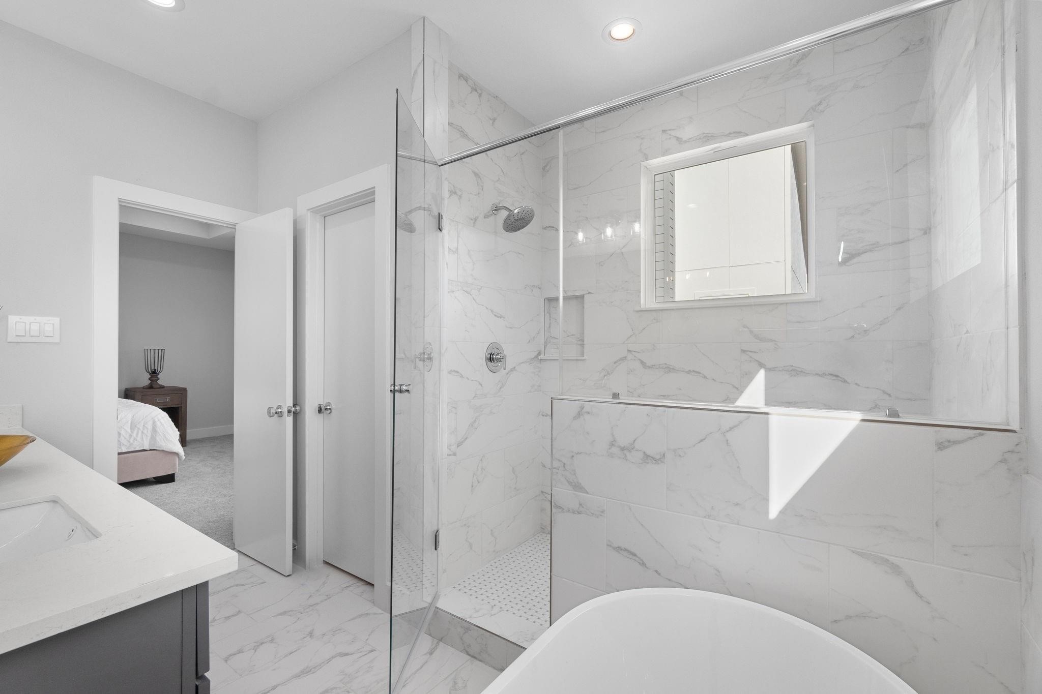 903 Quitman Street, Unit B Houston, TX 77009 - Photo 12 of 24 Luxurious spa-like bath with oversized walk-in shower, freestanding soaking tub, and full-height tile surround, delivering a sleek and modern aesthetic.