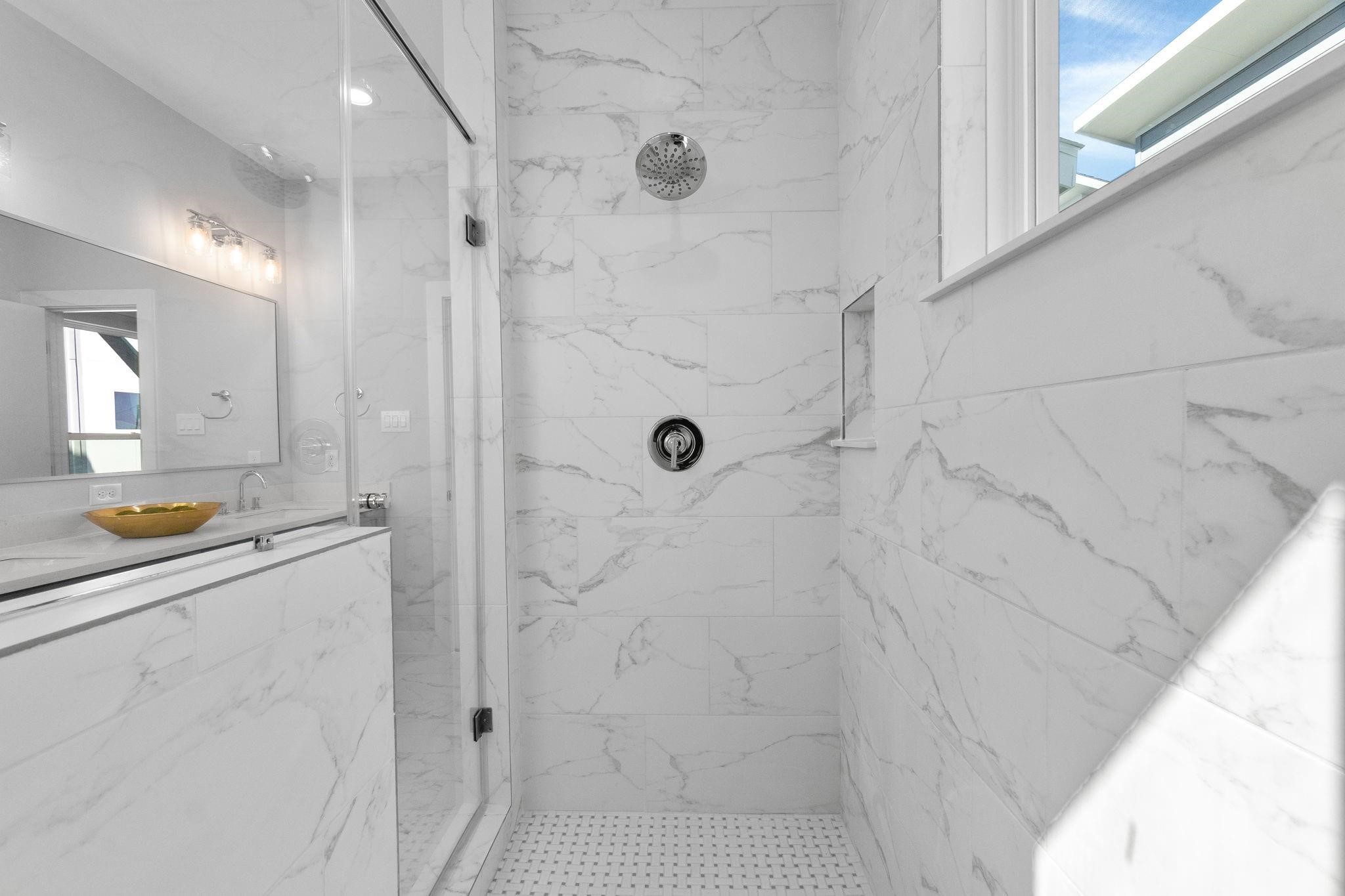 903 Quitman Street, Unit B Houston, TX 77009 - Photo 13 of 24 Spa-inspired walk-in shower featuring full-height marble-look tile, sleek glass enclosure, and a built-in niche for added functionality, creating a clean and luxurious feel.