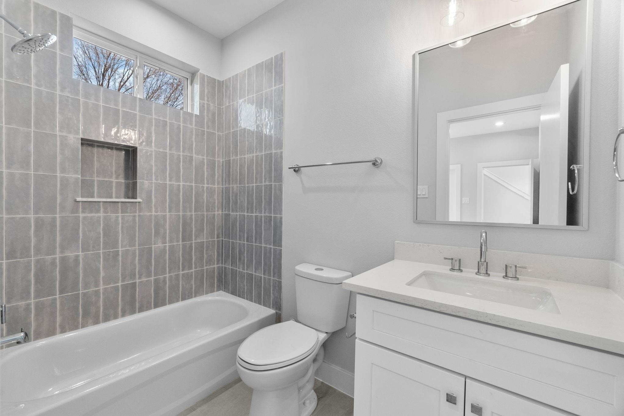 903 Quitman Street, Unit B Houston, TX 77009 - Photo 19 of 24 Bright full bath featuring a clean vanity with quartz countertops, modern fixtures, and a tiled tub/shower combination with built-in niche.