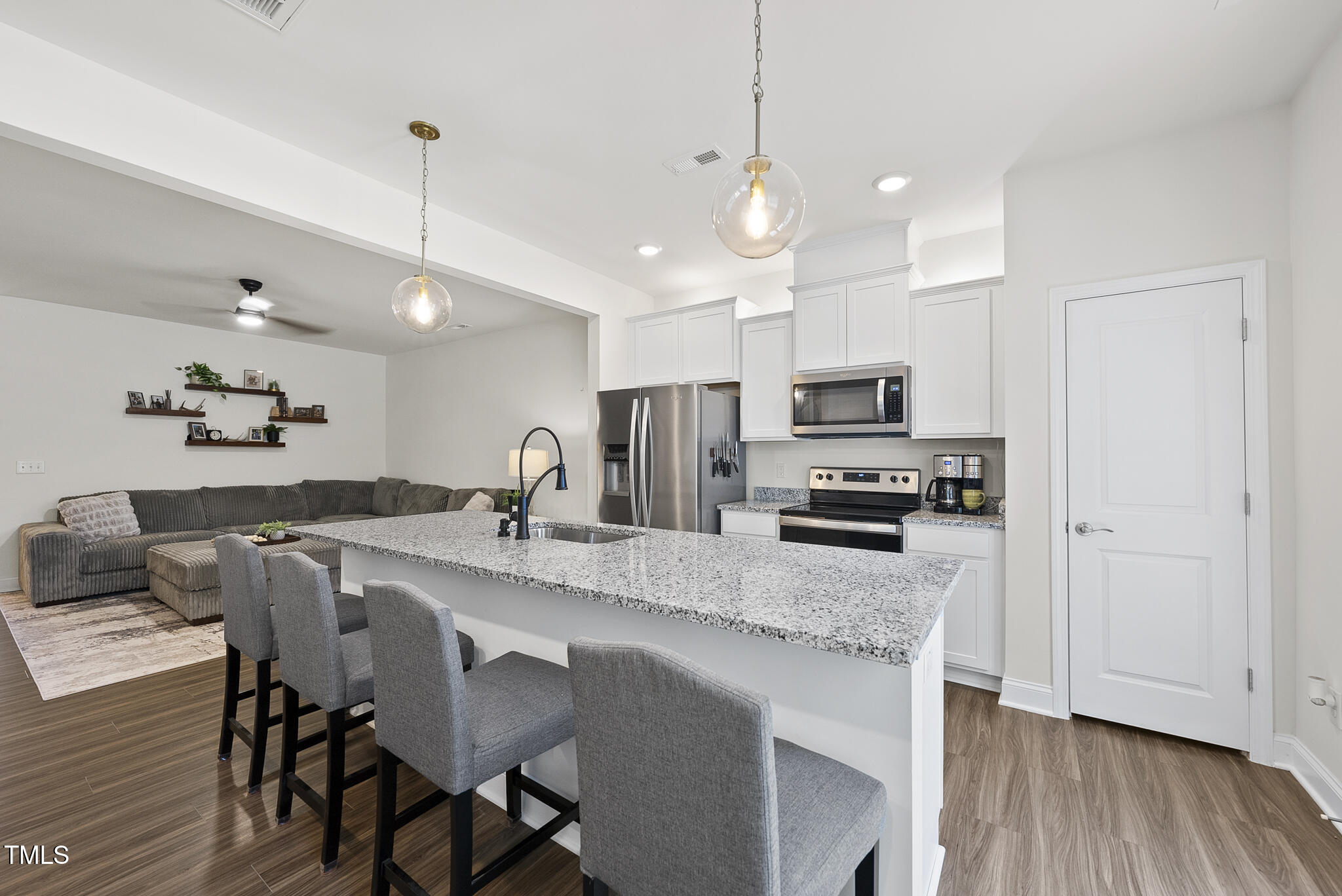 93 Begonia Street Angier, NC 27501 - Photo 11 of 29 a kitchen with stainless steel appliances granite countertop a stove top oven a refrigerator a sink and a dining table with wooden floor