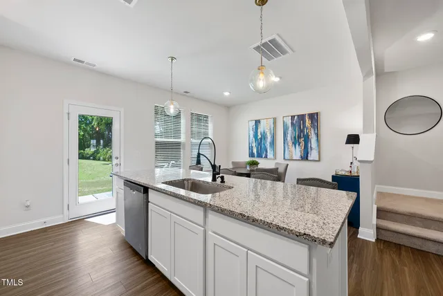 a dining room with stainless steel appliances granite countertop a dining table chairs refrigerator and kitchen view