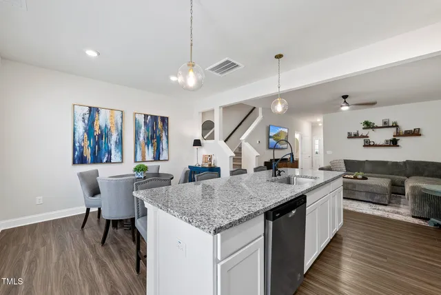 a kitchen with stainless steel appliances a dining table chairs stove and wooden floor