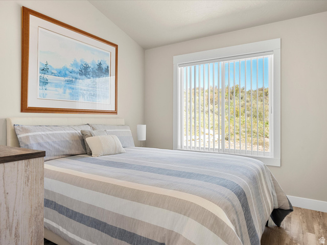 608 Fremont Road Fish Haven, ID 83287 - Photo 25 of 35 Vaulted ceiling bedroom with a large window featuring vertical blinds, wood-finish flooring, and light neutral wall paint
