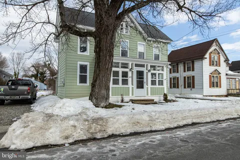 a view of a white house with a large tree in front of it
