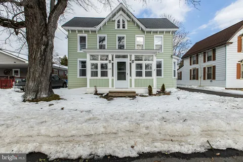 a front view of a house with a yard covered with snow