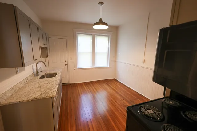 a kitchen with granite countertop a stove and a wooden floor