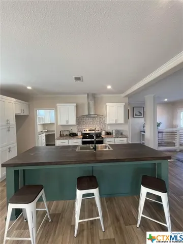 a kitchen with stainless steel appliances granite countertop a stove a sink dishwasher and a refrigerator with wooden floor