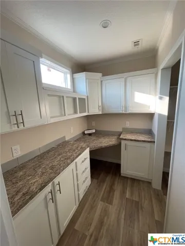 a kitchen with stainless steel appliances a white stove top oven and white cabinets next to a window