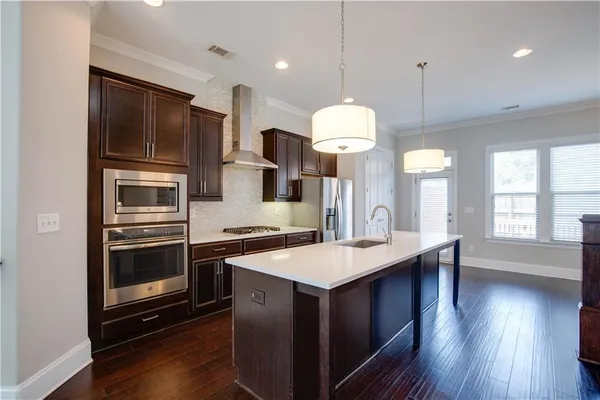 a kitchen with a sink stainless steel appliances and wooden floor