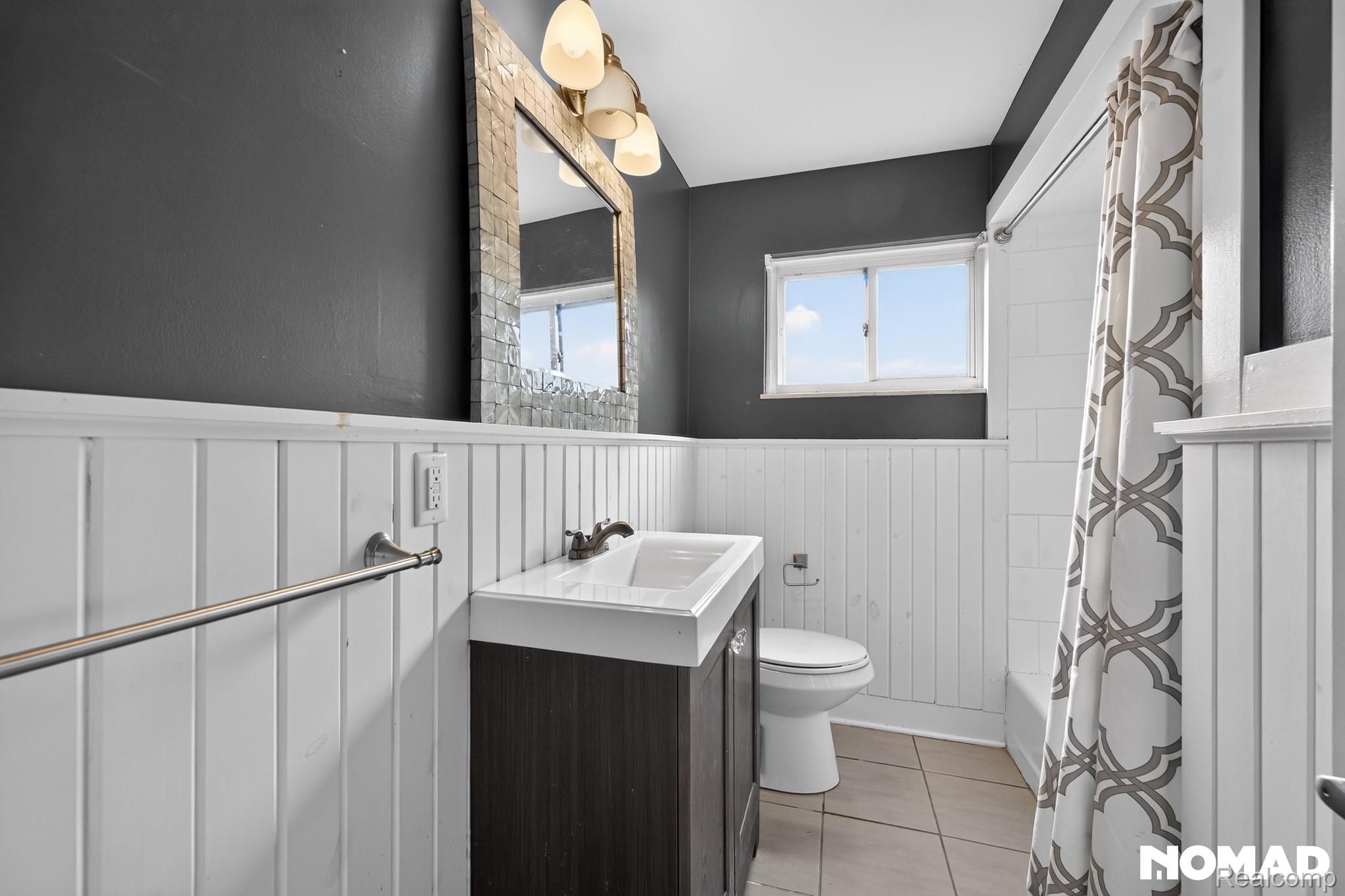 8315 Hilton Road Brighton, MI 48114 - Photo 21 of 26 Bathroom featuring a window, white board and batten wainscoting, a vanity with an integrated sink, a toilet, and a tiled floor