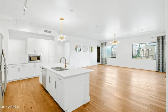 a kitchen with stainless steel appliances granite countertop a sink stove and white cabinets with wooden floor