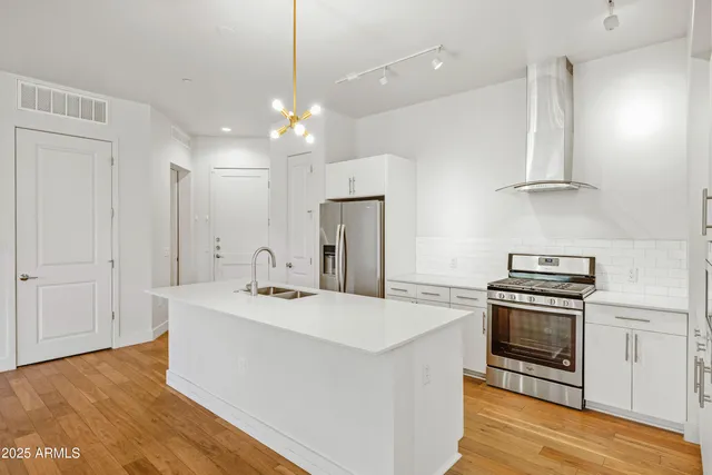 a kitchen with a sink stainless steel appliances and wooden floor