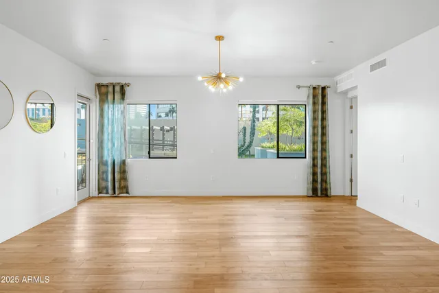 a view of an empty room with window and wooden floor