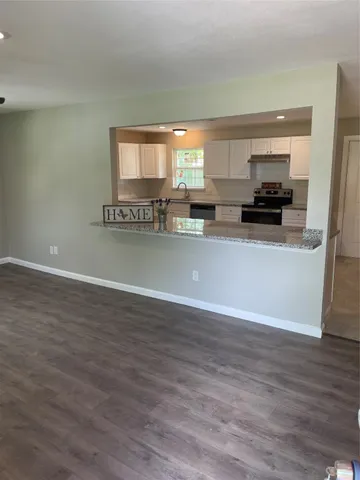 a view of a kitchen with stainless steel appliances wooden floor and a large window