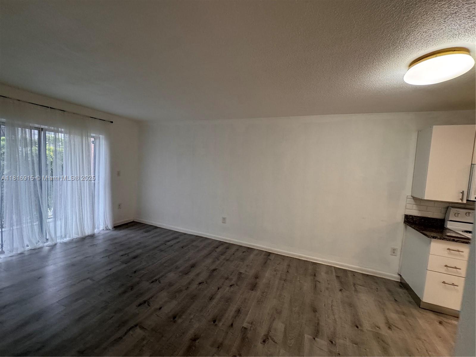 677 Southwest 9th Avenue, Unit 303 Miami, FL 33130 - Photo 5 of 34 an empty room with wooden floor and a window