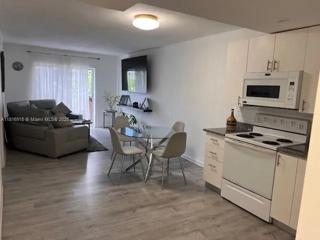 a living room with furniture a flat screen tv and kitchen view