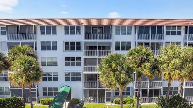 a front view of a building with balcony and garden