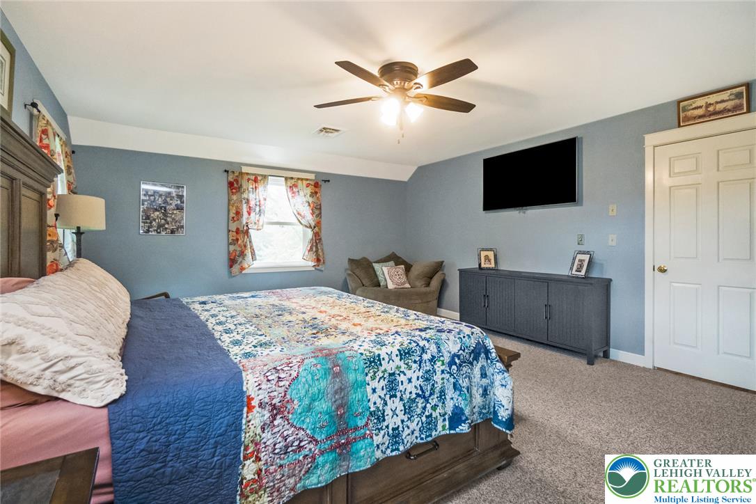 1553 Surrey Road Bethlehem, PA 18015 - Photo 34 of 92 A comfortable bedroom with a warm, inviting ambiance, illuminated by natural light and a ceiling fan.