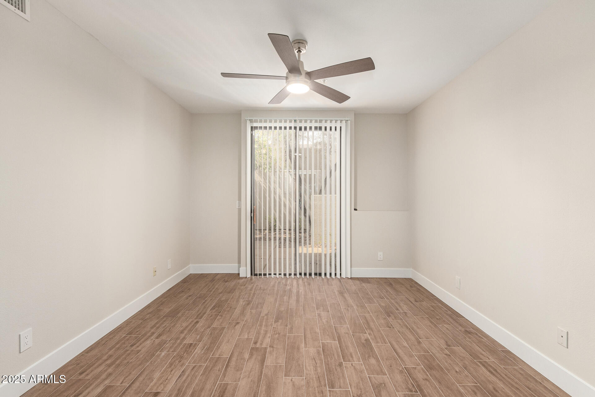7700 East Gainey Ranch Road, Unit 102 Scottsdale, AZ 85258 - Photo 18 of 40 an empty room with wooden floor ceiling fan and windows
