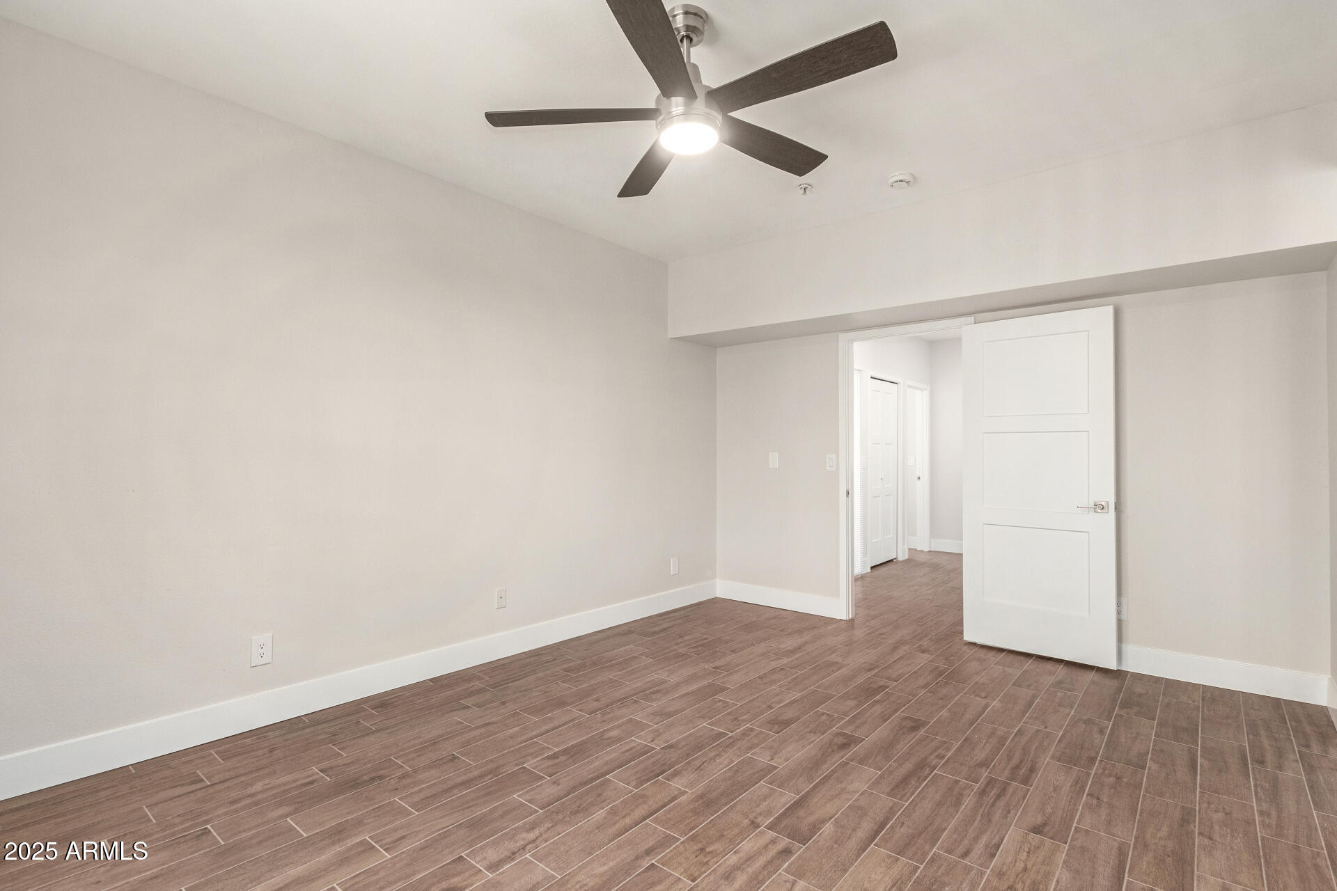 7700 East Gainey Ranch Road, Unit 102 Scottsdale, AZ 85258 - Photo 21 of 40 an empty room with wooden floor and windows