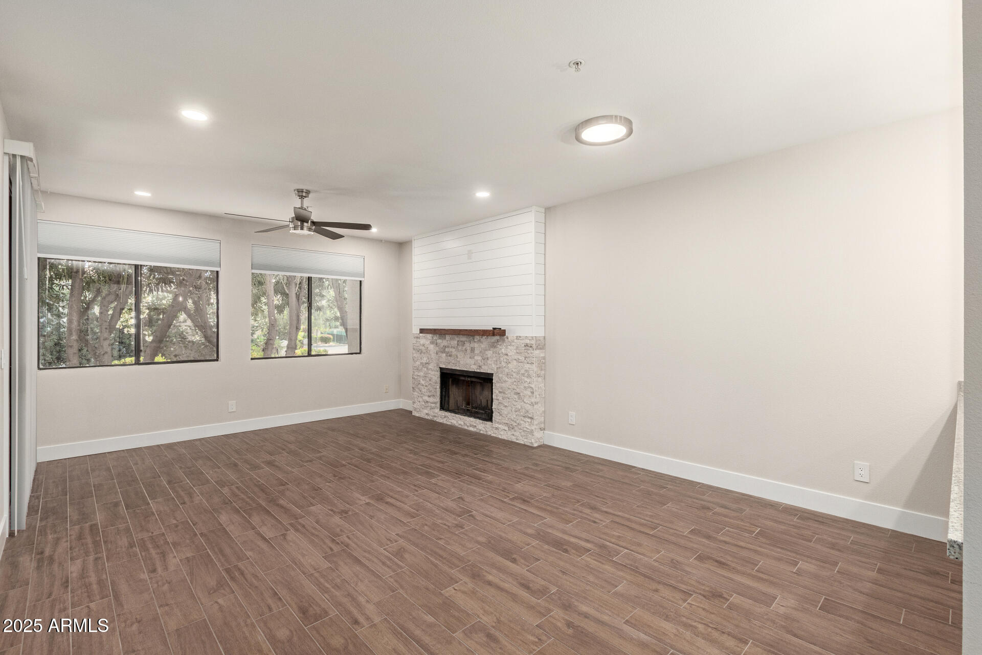 7700 East Gainey Ranch Road, Unit 102 Scottsdale, AZ 85258 - Photo 6 of 40 an empty room with wooden floor fireplace and windows