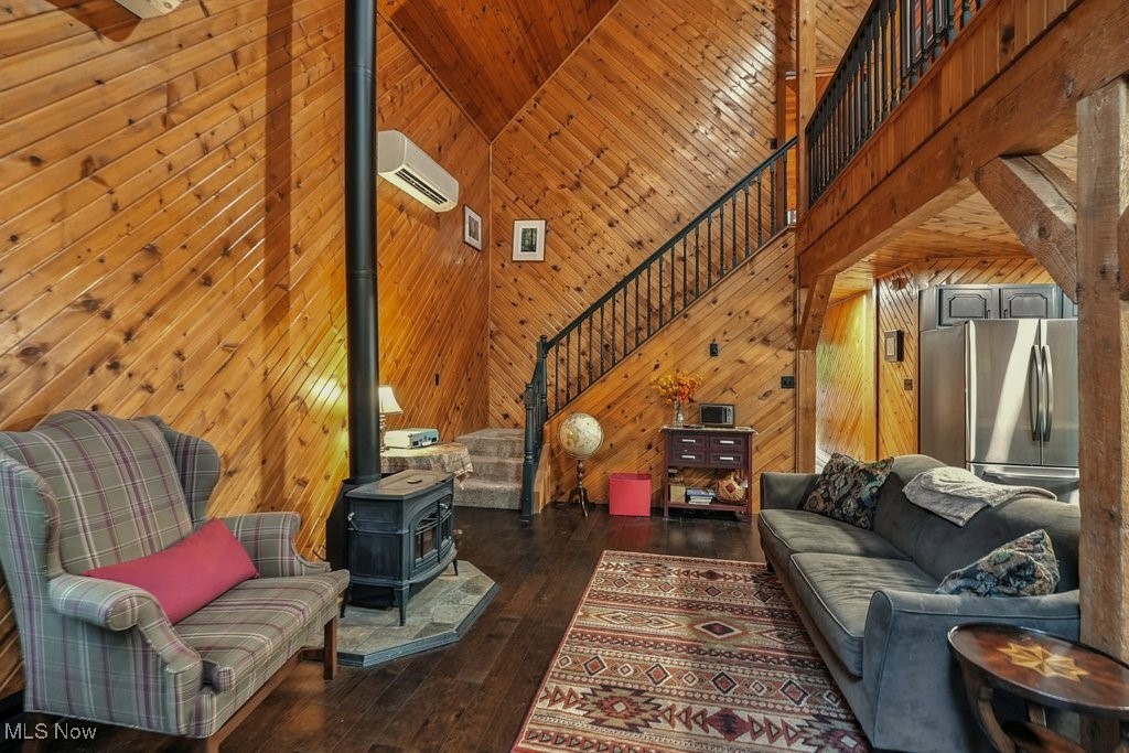 6711 Booth Road Ravenna, OH 44266 - Photo 17 of 50 Living area with wooden walls, a wood stove, stairs, high vaulted ceiling, and dark wood-type flooring