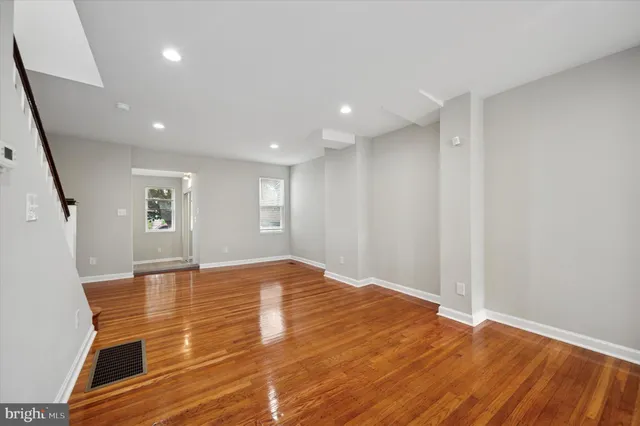 a view of an empty room with wooden floor and stairs