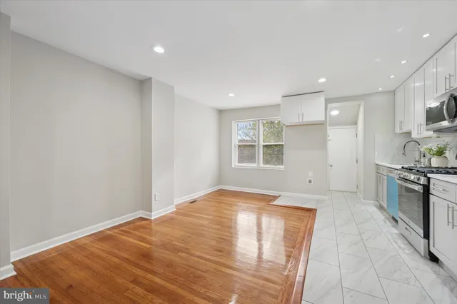 a view of a kitchen with a sink and dishwasher a stove top oven with wooden floor