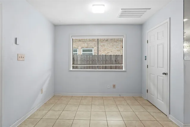 a view of an empty room with window and chandelier fan