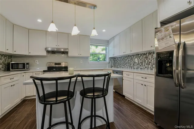 a kitchen with stainless steel appliances granite countertop a white table chairs refrigerator and sink