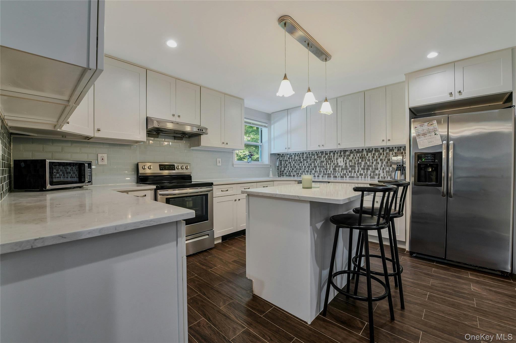 27 Upper Sheep Pasture Road East Setauket, NY 11733 - Photo 8 of 25 a kitchen with stainless steel appliances a microwave a stove a sink dishwasher a refrigerator white cabinets and wooden floor